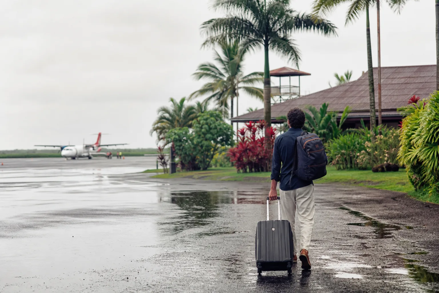 Voyageur avec une valise dans un environnement tropical près d’un petit aéroport